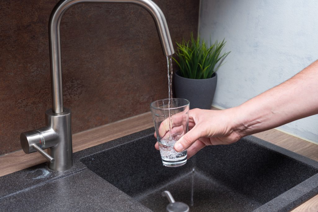 Remplissage d’un verre d’eau sous un robinet moderne dans une cuisine contemporaine.
