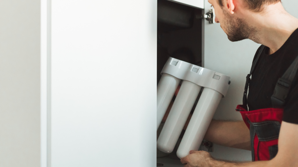 Professionnel en train d'installer un petit adoucisseur d'eau dans le placard d'un appartement