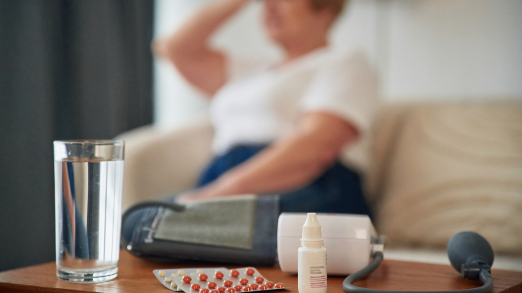 Verre d'eau adoucie disposé avec des éléments médicaux sur une table devant une personne faisant de l'hypertension