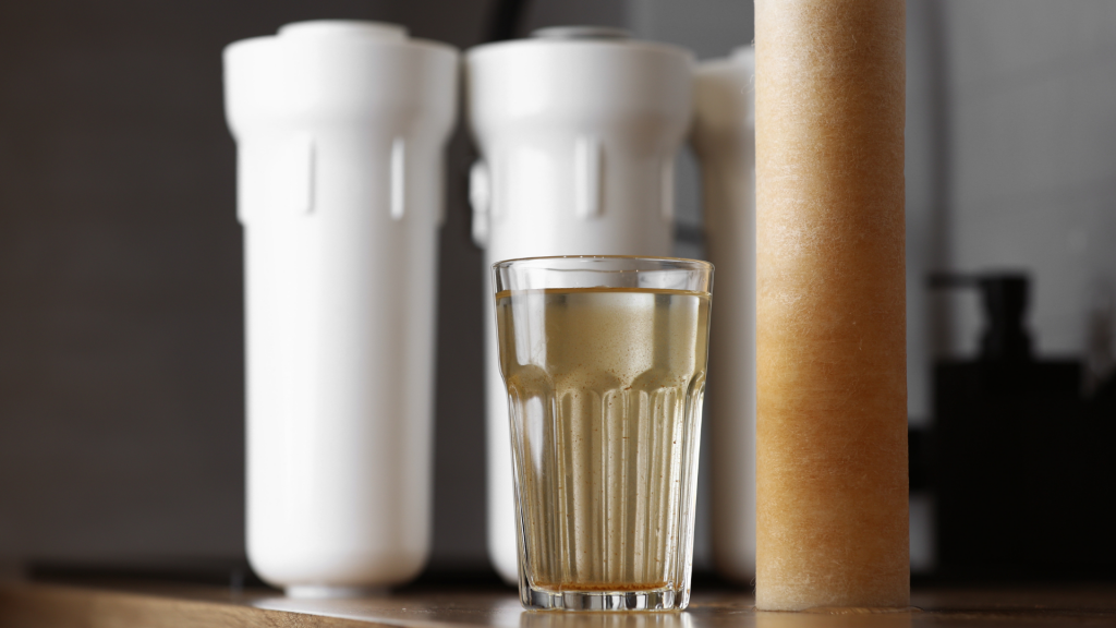 Verre d'eau impure disposé à côté d'un vieux filtre et de nouveaux filtre d'adoucisseur d'eau